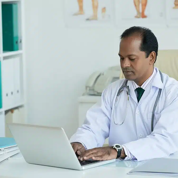 Mature doctor working on a laptop web