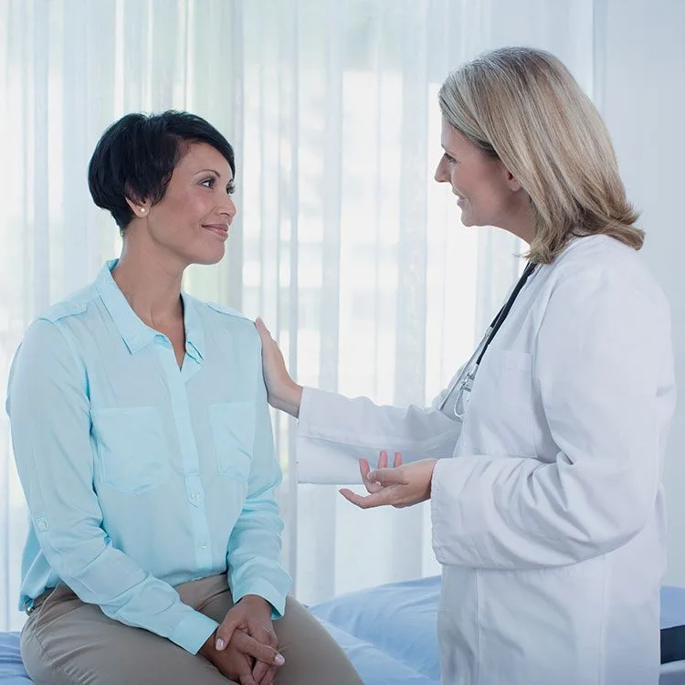 Smiling doctor talking to patient in office web