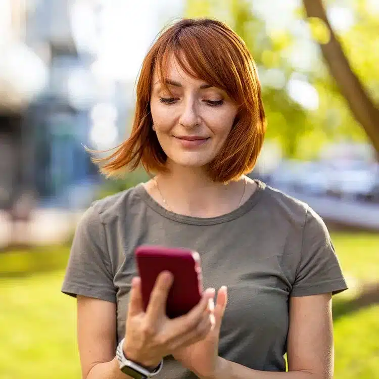 Smiling woman using a smartphone in the city web