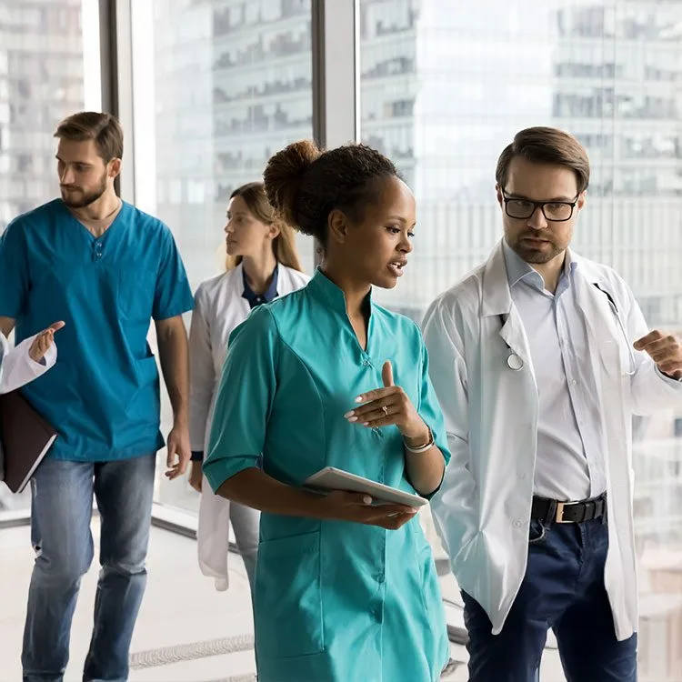 Team of medical professionals walking together in hospital office hallway discussing difficult medical cases web