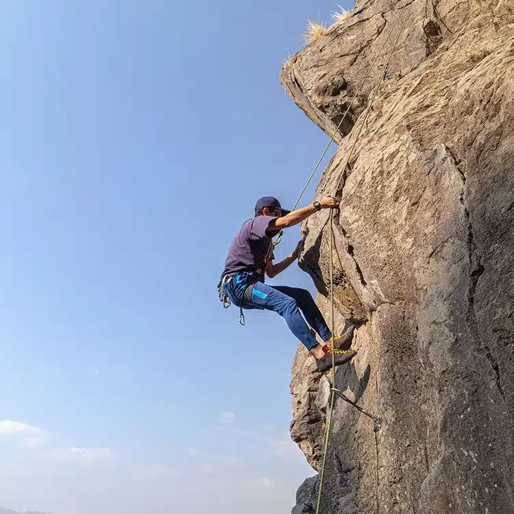 Young male climbs a rocky cliff web